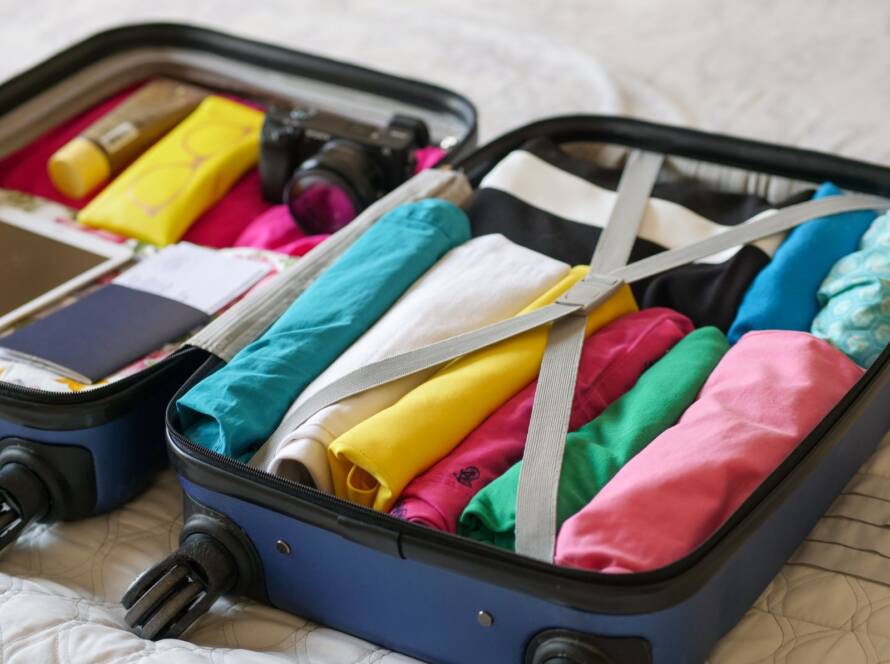 Open suitcase packed with clothes and travel essentials