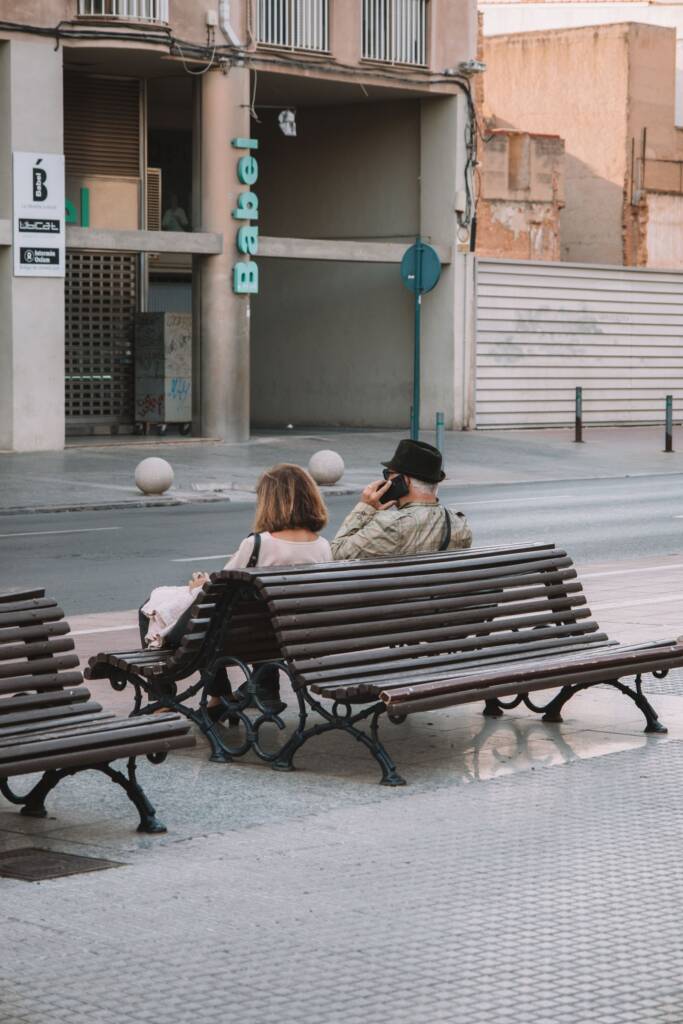 People relaxing on benches in a quiet Valencia street